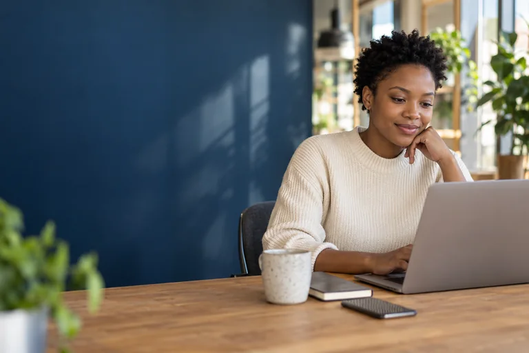 A learner studying independently at her laptop in a bright workspace